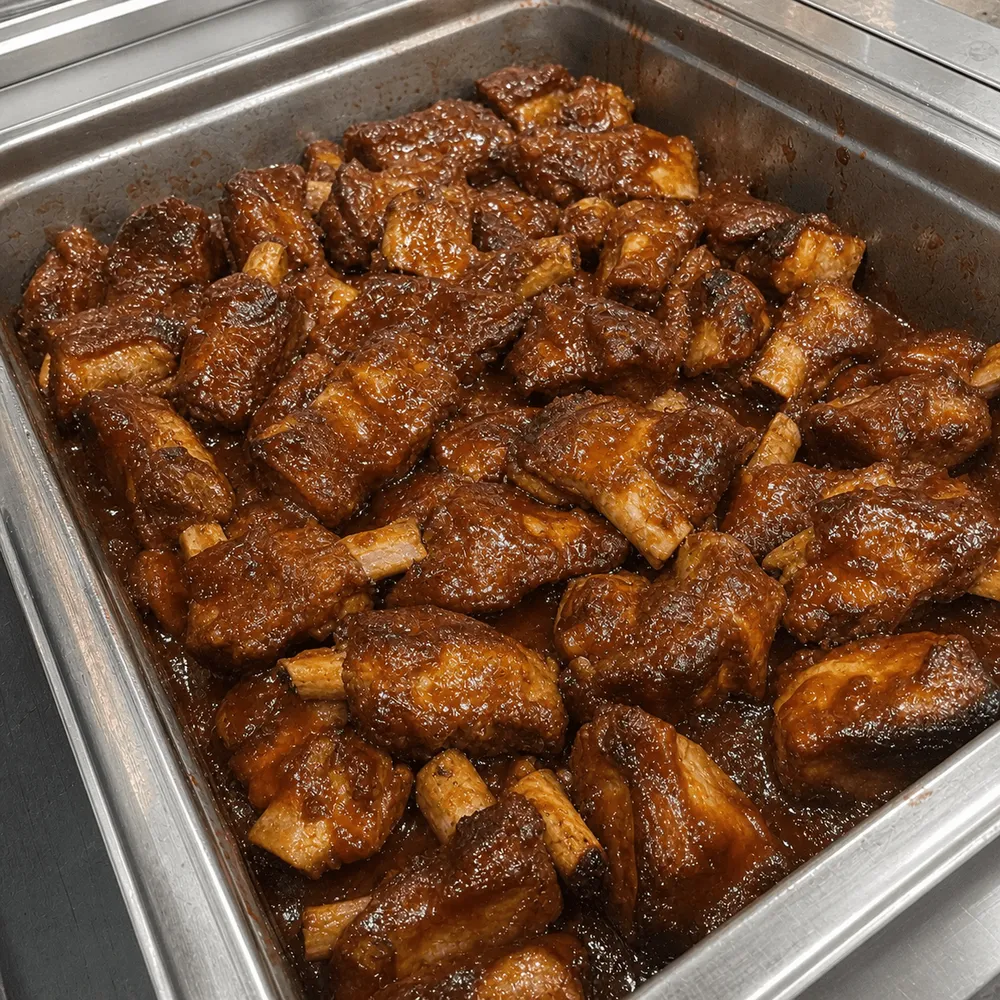 Glazed BBQ ribs in a stainless-steel buffet pan