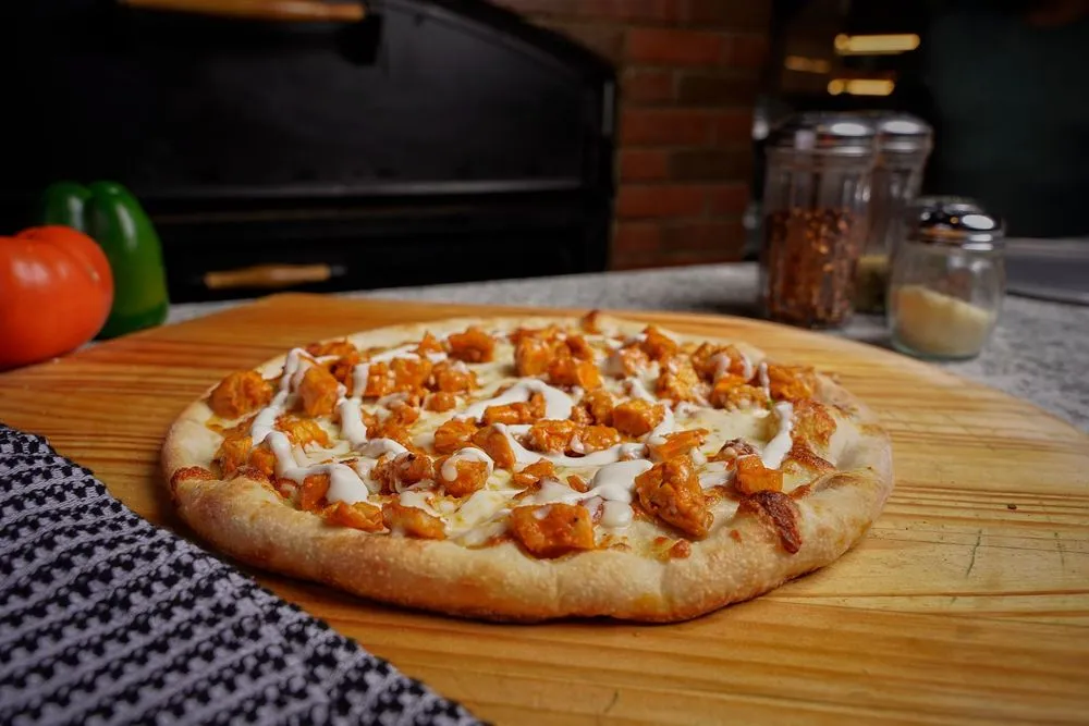 Donabella Restaurant Pizzeria pizza on a wooden board with sauce, cheese, and kitchen condiments