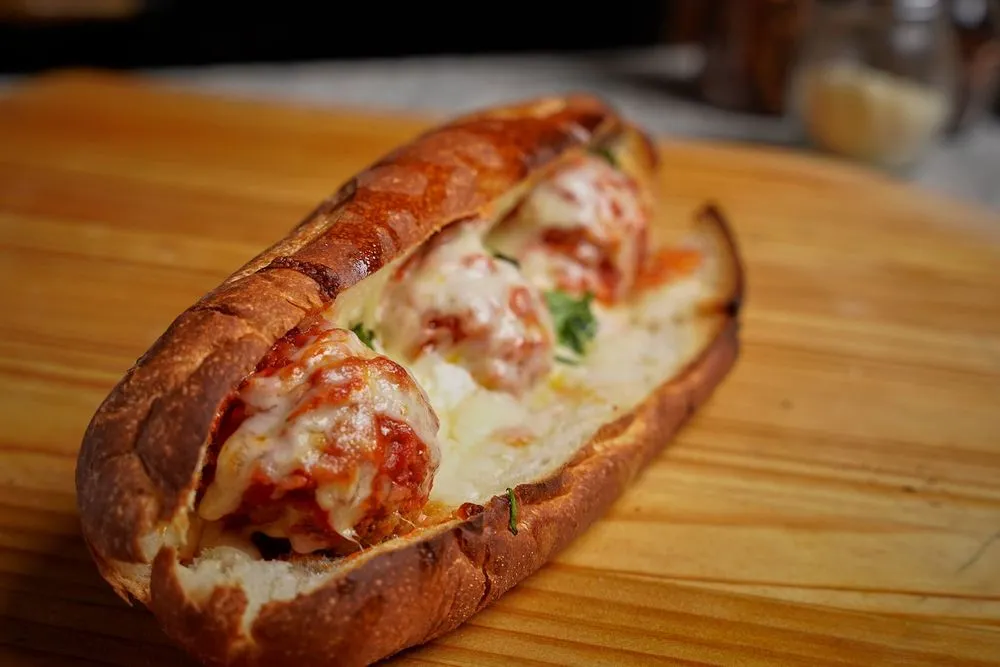 Baked meatball sandwich with melted cheese on a wooden board