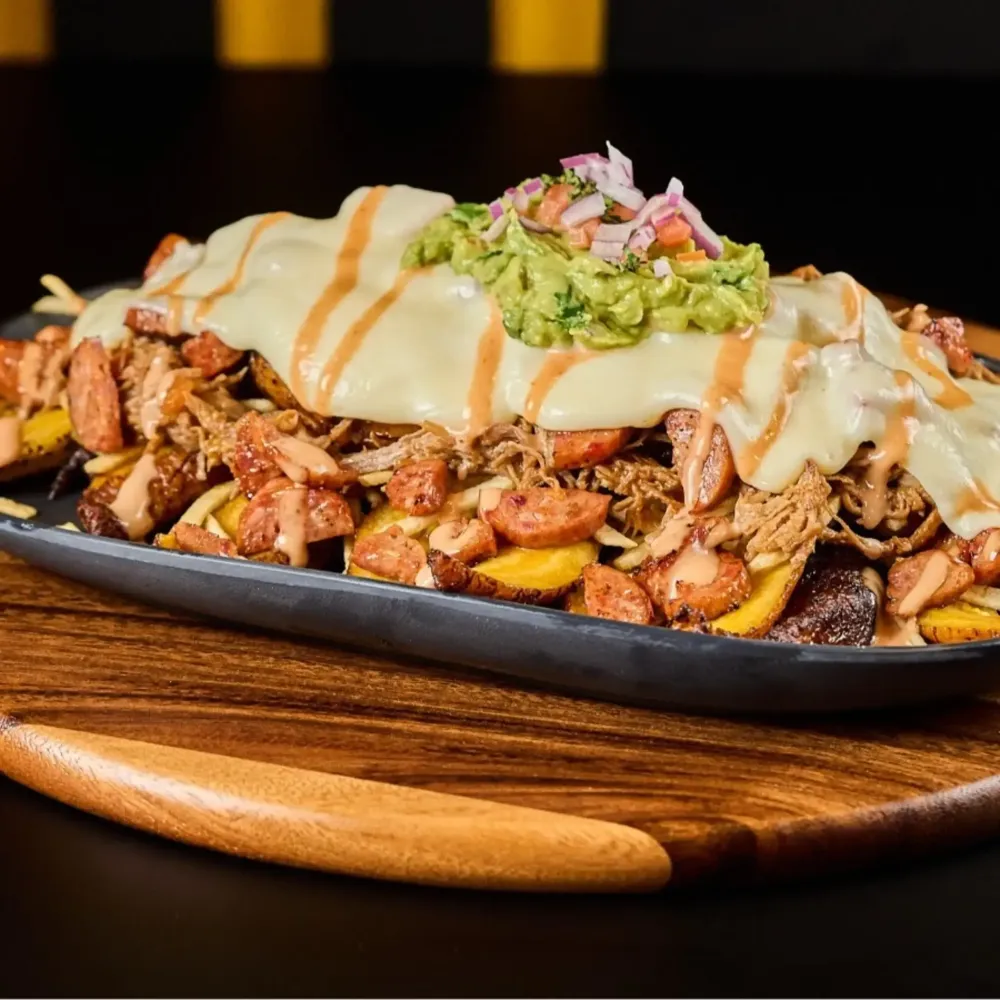 Loaded Colombian salchipapa with meats, sausage and guacamole at Monchy's