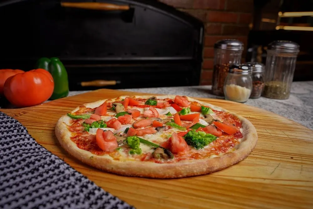 Veggie pizza on a wooden board in Donabella Restaurant Pizzeria's warm kitchen setting