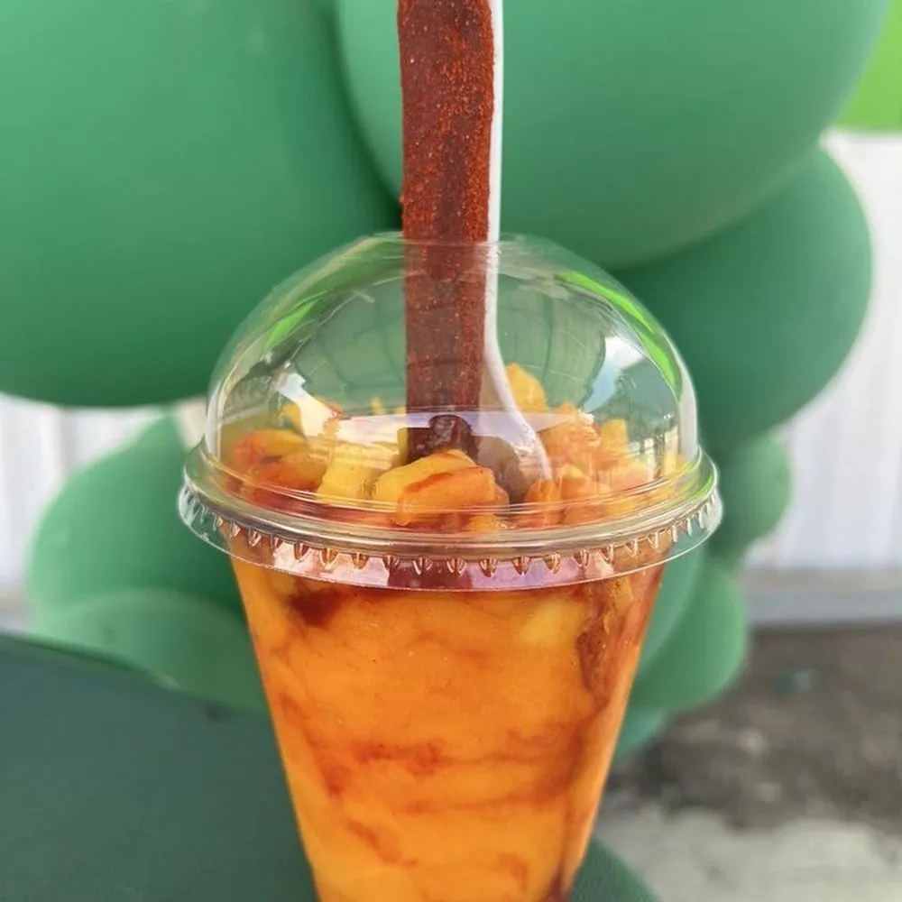 A mangoneada cup with chopped mango, chamoy and a tamarind straw