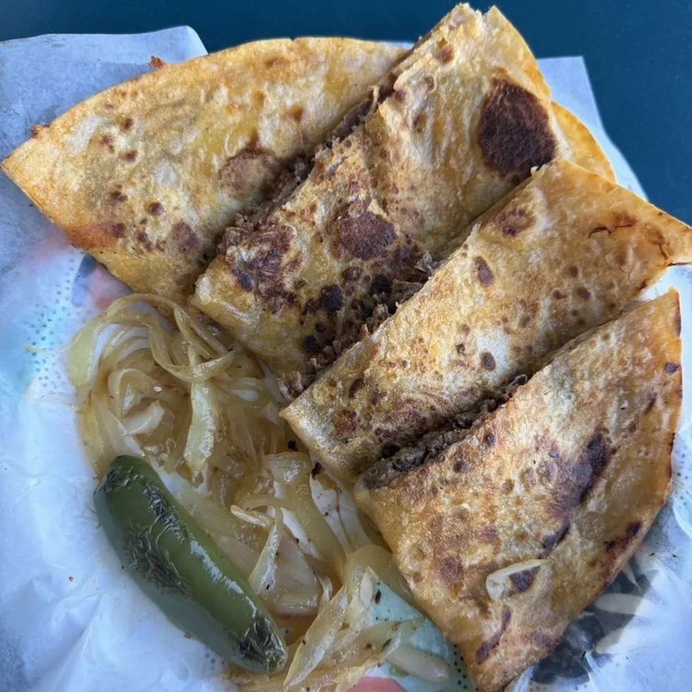 Four crispy birria tacos with grilled onion and a roasted jalapeno