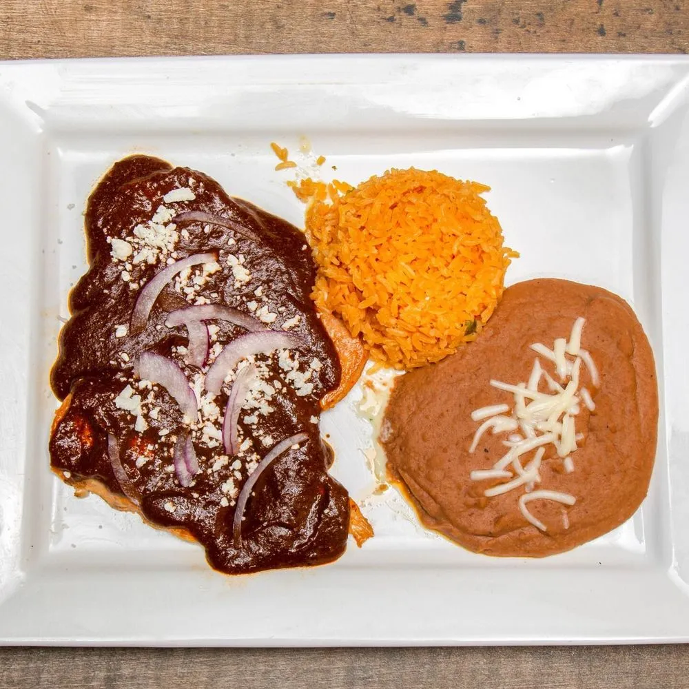 Enchiladas in mole sauce with rice and refried beans