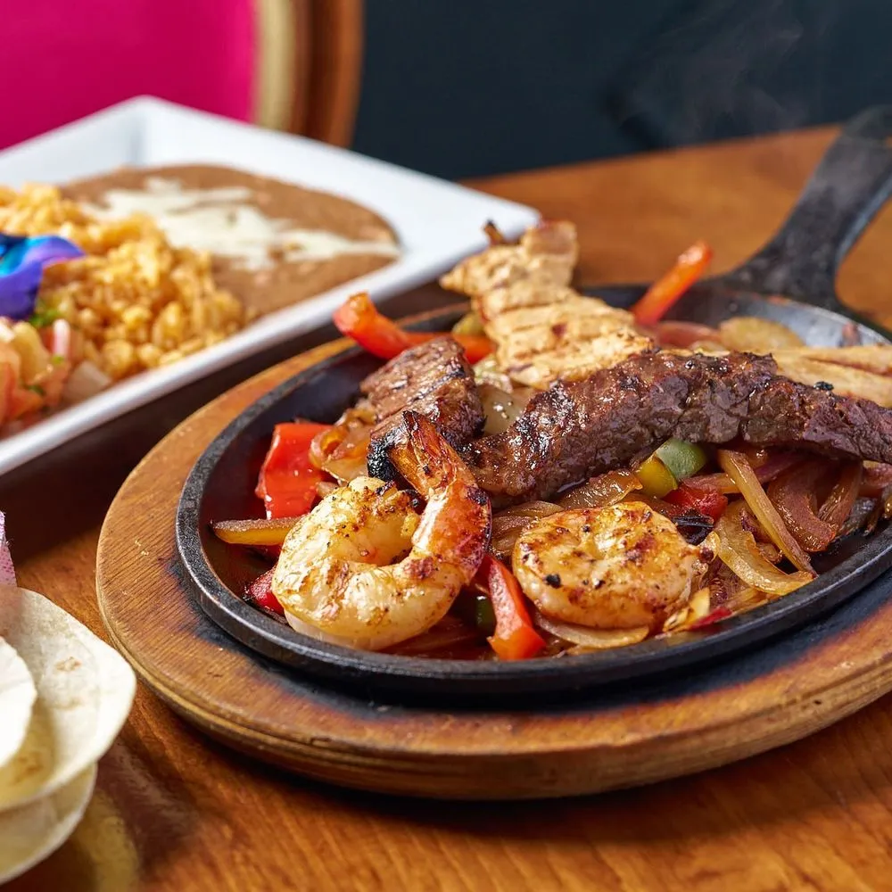 Fajitas arriving on a sizzling skillet with peppers and onions