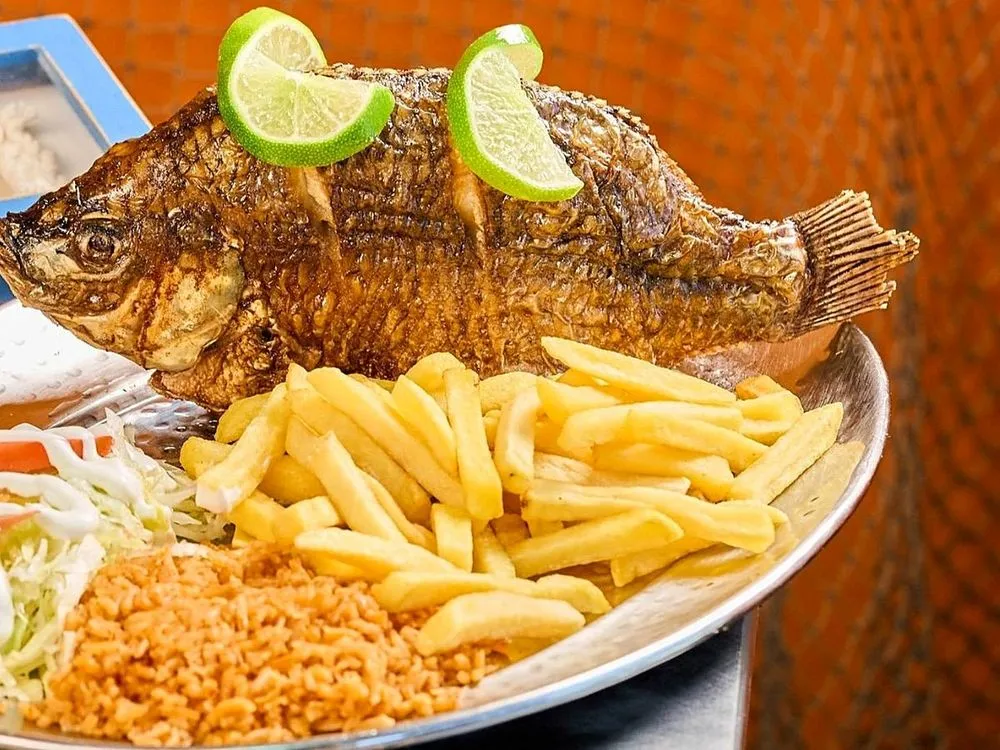 Whole fried mojarra with lime, fries, rice and salad
