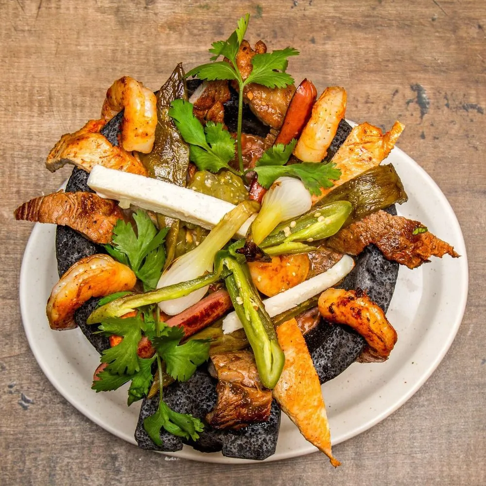 Molcajete off the grill with steak, nopal, spring onions and roasted chiles