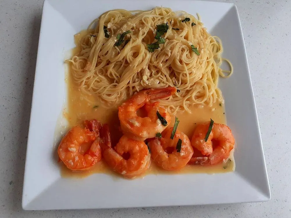 Shrimp scampi with garlic and lemon next to angel hair pasta