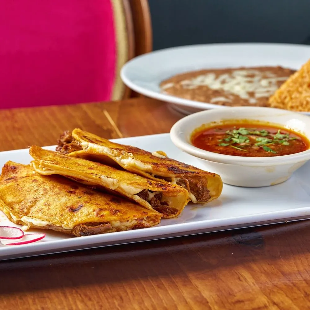 Birria tacos with melted cheese and consomme for dipping