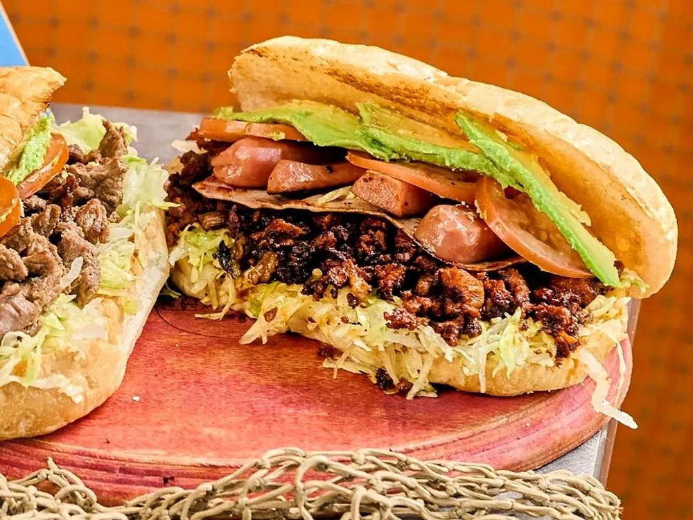 Loaded Mexican torta with chorizo, sausage, ham, avocado, tomato and lettuce