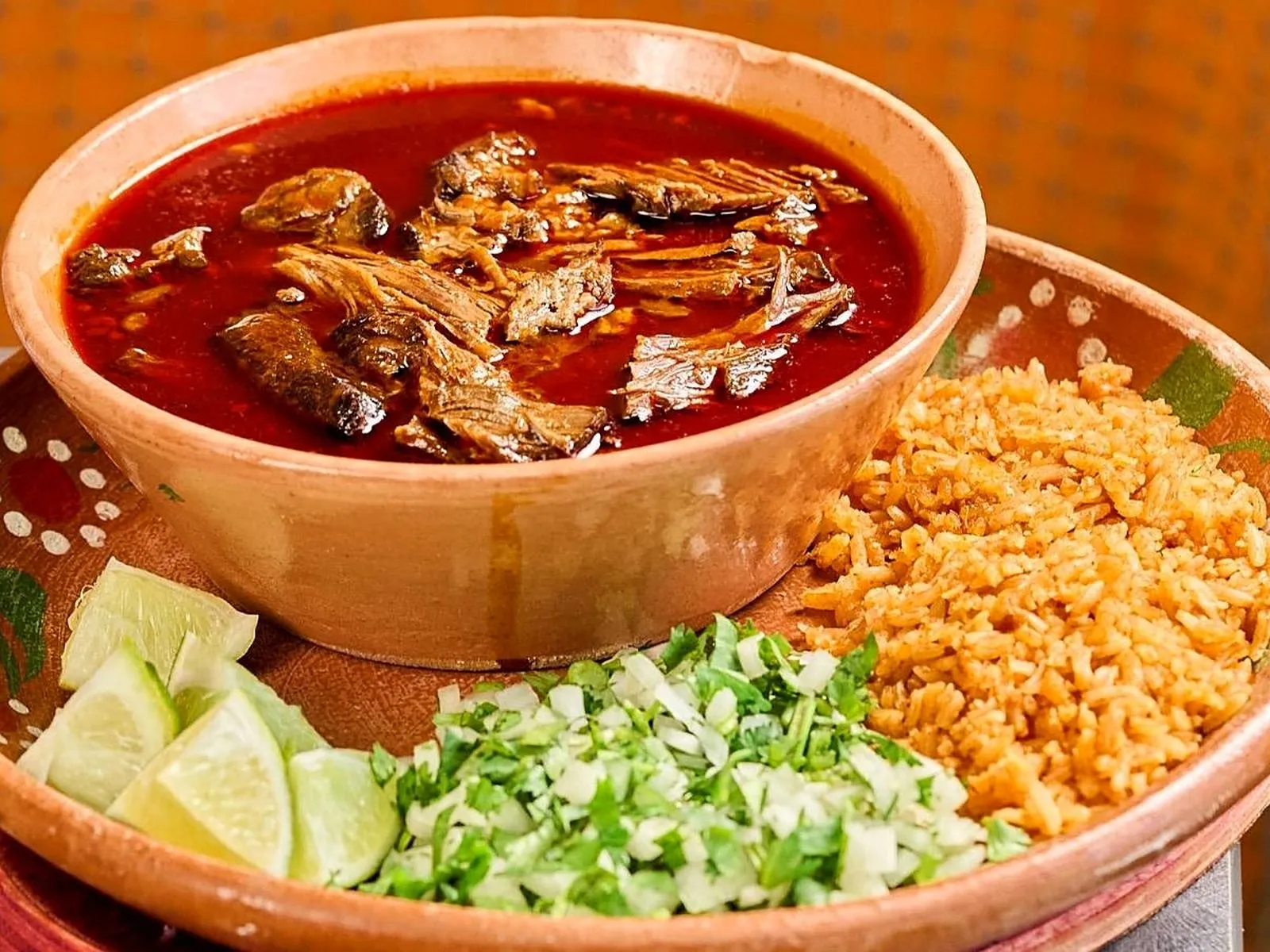 Birria plate with red consomé, Mexican rice, onion, cilantro and lime