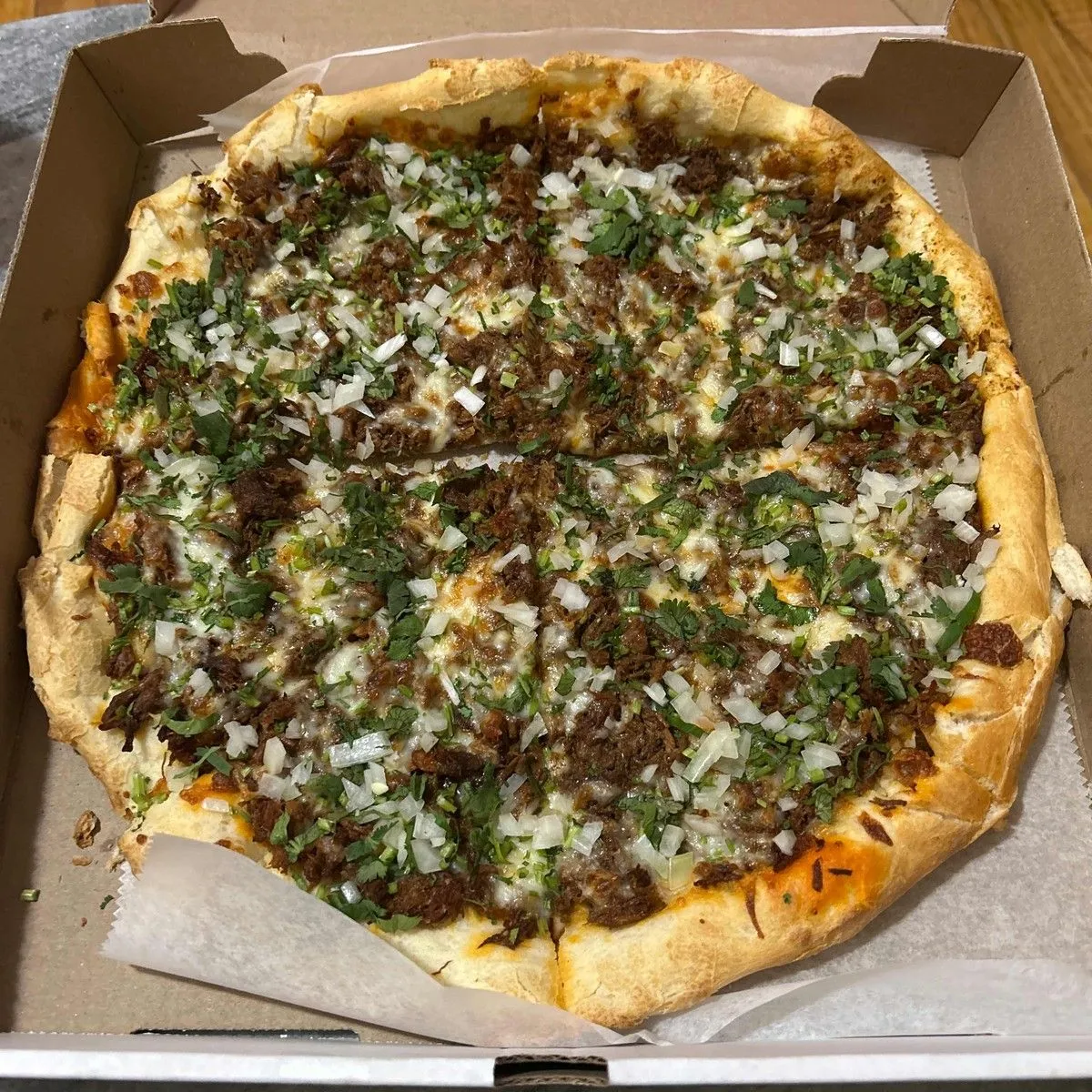 Birria pizza topped with juicy beef, cilantro and onion