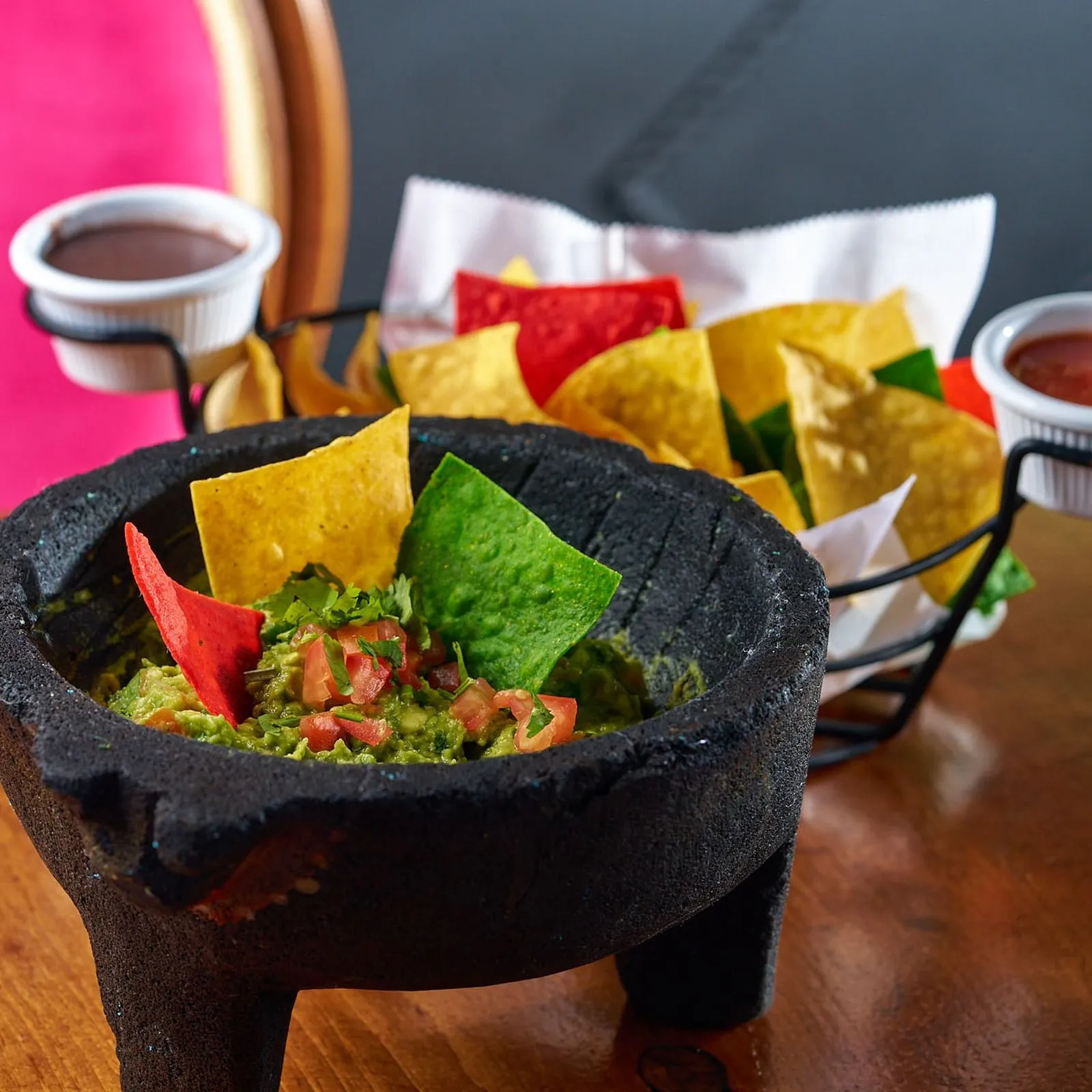 Guacamole served in a stone molcajete with peppers and tortilla chips